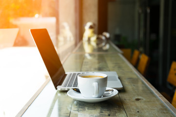 cup of coffee with latte art and modern laptop on wood floor