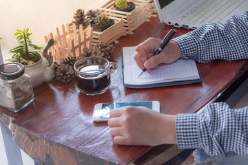 Businessman writing with a pen in a notebook in a coffee shop.