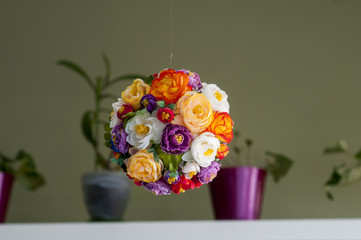 Multicolored artificial flowers collected in a ball weigh on the ceiling.