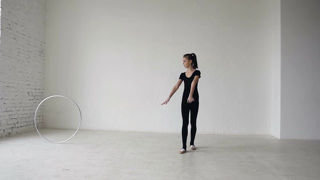Girl trains with a gymnastic hoop. Rhythmic gymnastics: Blonde girl training a gymnastics exercise with a hoop at gymnastics school at white background