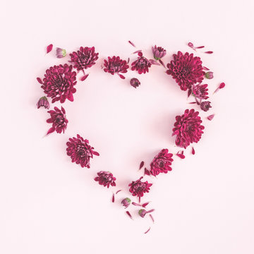 Flowers composition. Heart symbol made of chrysanthemum flowers on pink background. Flat lay, top view, copy space, square