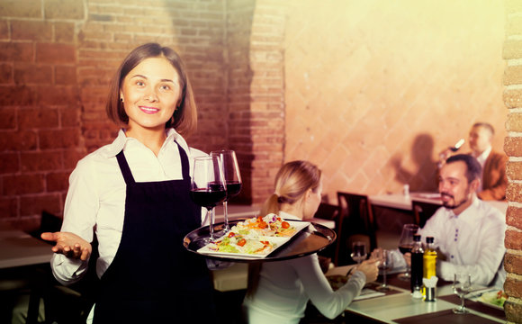 woman waiter demonstrating restaurant to visitors
