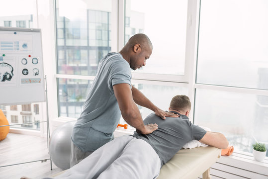 Professional orthopedics. Skillful nice orthopedist working with his patient while doing a massage for him