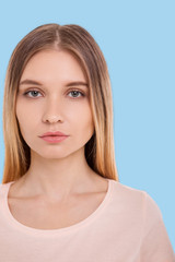 Naklejka premium Delicate beauty. The portrait of a charming young woman in a beige t-shirt posing for the camera while standing isolated on a blue background