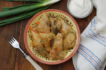 Stuffed Rolled Cabbage meat in Leaves in a Ceramic Plate with White Napkin,Parsley on a Rustic Wooden background. Traditional Romanian Russian Ukrainean Food.