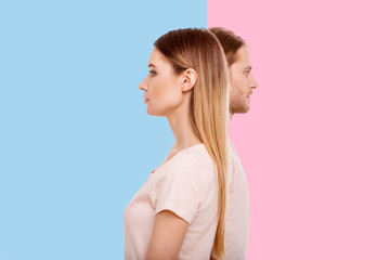 Diverging views. Pleasant young woman and her boyfriend standing in a line but looking into different directions while posing against blue and pink backgrounds respectively - obrazy, fototapety, plakaty