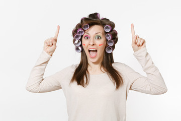 Happy woman with curlers pointing index fingers up on copy space isolated on white background....