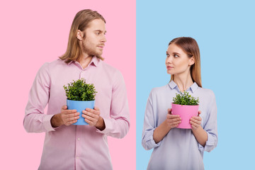 We love gardening. Pleasant young woman and her boyfriend looking at each other while holding...