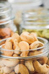 Various nuts and seeds in glass jars over white wooden table against white background. The concept of vegetarian and organic food. Set of photos.