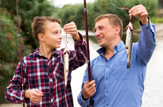 Man with teenager boy showing catch fish