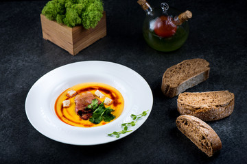 An appetizing pumpkin soup is served in a white plate in a restaurant