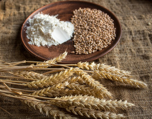wheat flour and spikelets of wheat on sackcloth background