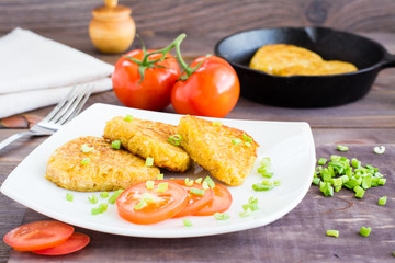 Crispy hash browns and tomatoes on a plate on a wooden table