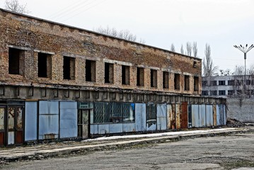 Fototapeta na wymiar ruins of a brick building with empty windows behind an iron fence