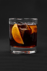 A single-colored transparent cocktail, refreshing in a low glass with radiant ice cubes with taste of berries, cola and slice, lime quartet. Side view Isolated black background