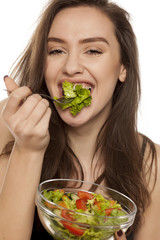 Happy young woman eat letuce salad on white background