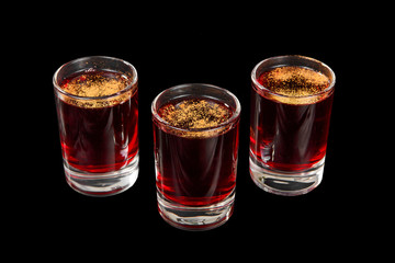 Monochrome transparent cocktails, a set of shots pile, wedge, three servings, with taste of berries, cherries, strawberries, greiprut, cola, with spices. Side view from above Isolated black background