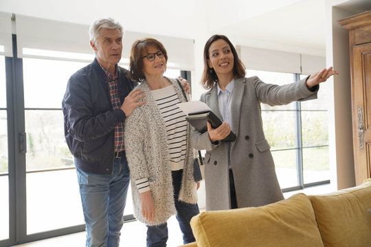 Senior couple with real estate agent visiting contemporary house