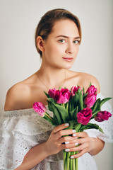 Studio shot of young beautiful girl holding purple tulip flowers