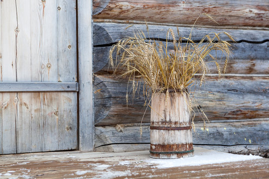 Old wooden bucket with weat bouquet at the porch of wooden house