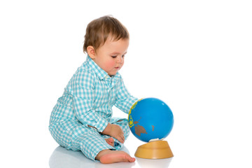 A little boy is playing with a globe.