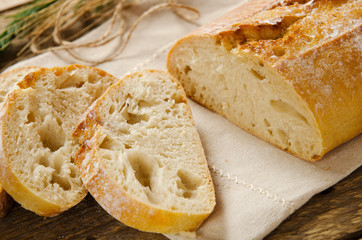 Ciabatta bread. Slices of ciabatta on wooden table on linen cloth. Rustic style, italian. Background - obrazy, fototapety, plakaty