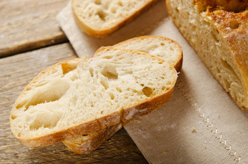Ciabatta bread. Slices of ciabatta on wooden table on linen cloth. Rustic style, italian. Top view, background