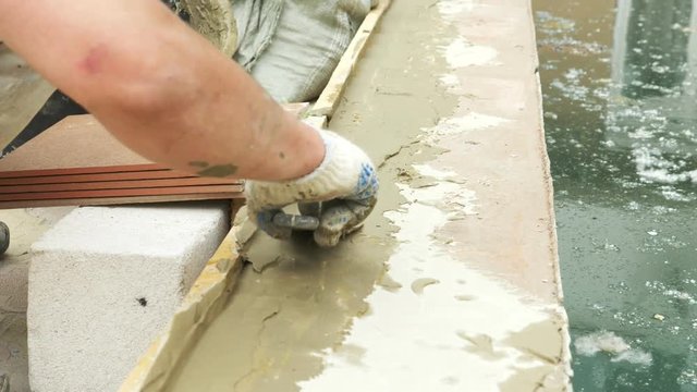 spatula and bucket with mortar on the construction site. the builder finishes the surface with plaster. 4k. pool repair.