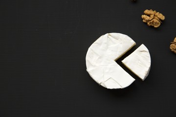Cheese camembert or brie with walnuts on dark background. Milk production. Top view. Flat lay. Copy space.