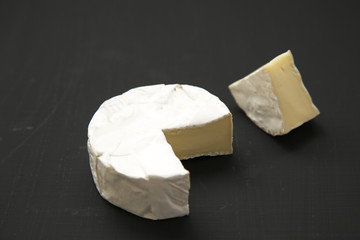 Cheese camembert or brie on dark background. Milk production. Side view. Closeup.
