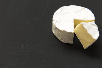 Cheese camembert or brie on dark background. Milk production. Side view. Closeup. Copy space.