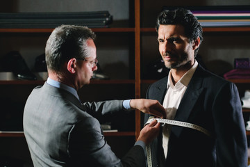 Portarit of a tailor while making a business suit using the tape measure. Concept: Fashion,...
