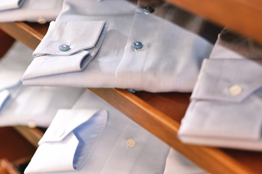   Close up of new white folded shirts on a shelf of a shop or a shelf of a closet. concept: fashion, tailor, shopping