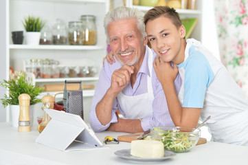 Obraz na płótnie Canvas Senior man with grandson preparing dinner in kitchen