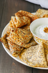 Delicious poppy seed crepes (blinis) and sour cream sauce with dill served on a white plate on a wooden background.