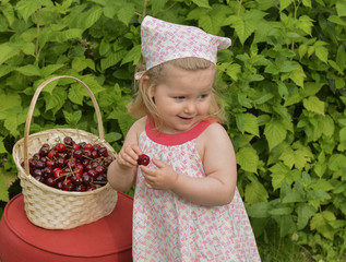 A girl in a dress is holding a cherry in her hands