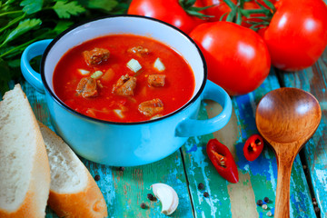Tomato soup in a blue bowl. Rustic style. Wooden background.