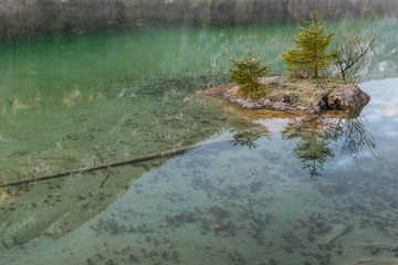 Kleine Insel aus Stein mit Bäumen im See in den Bergen