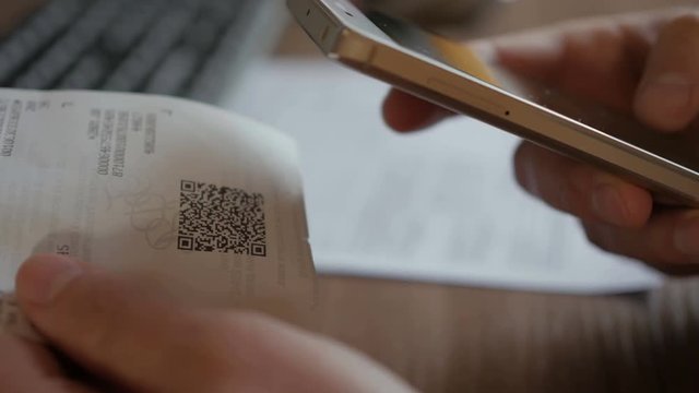 A man scans the QR code on a check from a supermarket.