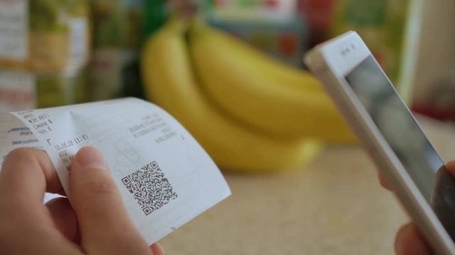 A man scans the QR code on a check from a supermarket.