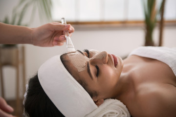 Beauty salon. Nice attractive woman having a mask applied on her face while caring about her skin