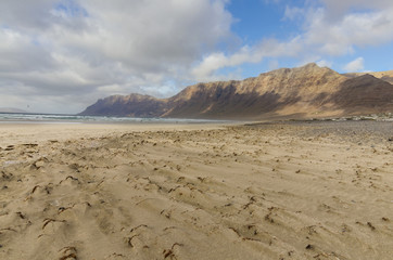 Famara beach on Lanzarote with huge cliffs and dramatic sky