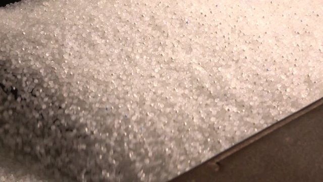 Plastic granules in container of the extrusion equipment. Shot in slow motion