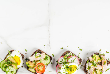 Set of various danish open sandwiches Smorrebrod with fish, egg and fresh vegetables, white marble background copy space top view