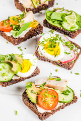 Set of various danish open sandwiches Smorrebrod with fish, egg and fresh vegetables, white marble background copy space