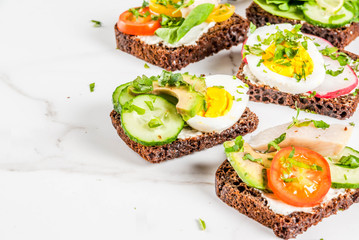 Set of various danish open sandwiches Smorrebrod with fish, egg and fresh vegetables, white marble background copy space