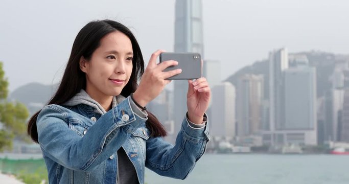 Woman taking photo on cellphone in city