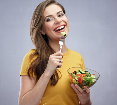 Youg woman eating salad from glass bowl.