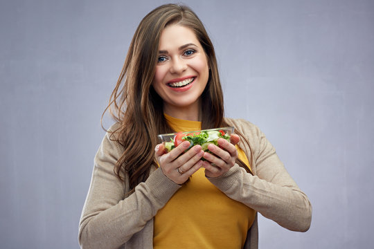 Smiling girl holding glass bowl with healthy food salad.