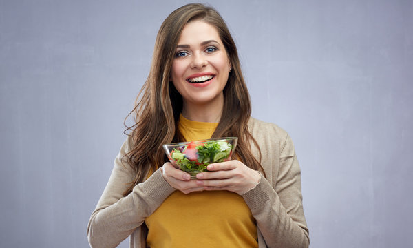 Beautiful smiling girl holding salad bowl.